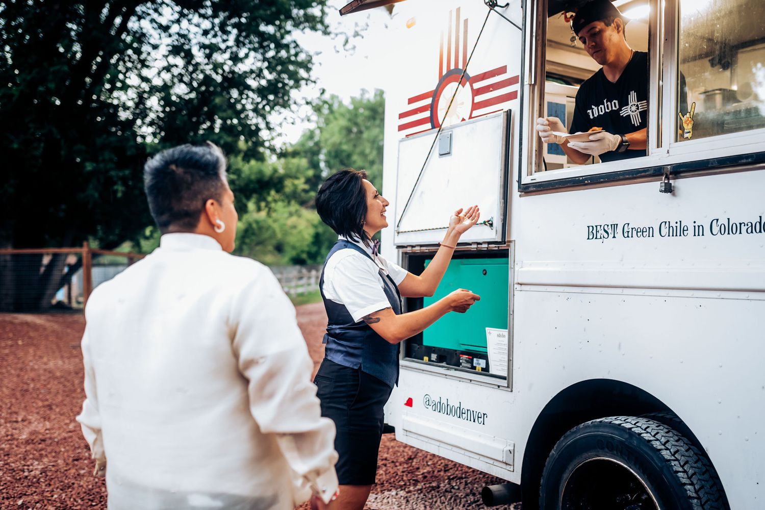 Guests ordering from a white food truck at an outdoor event.