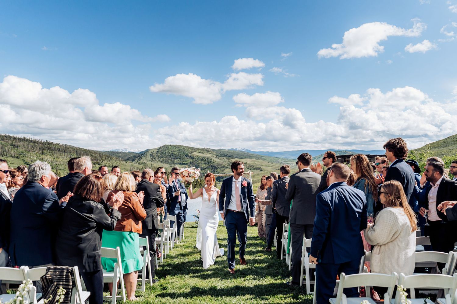 Wedding guests standing and celebrating during outdoor mountain ceremony recessional.