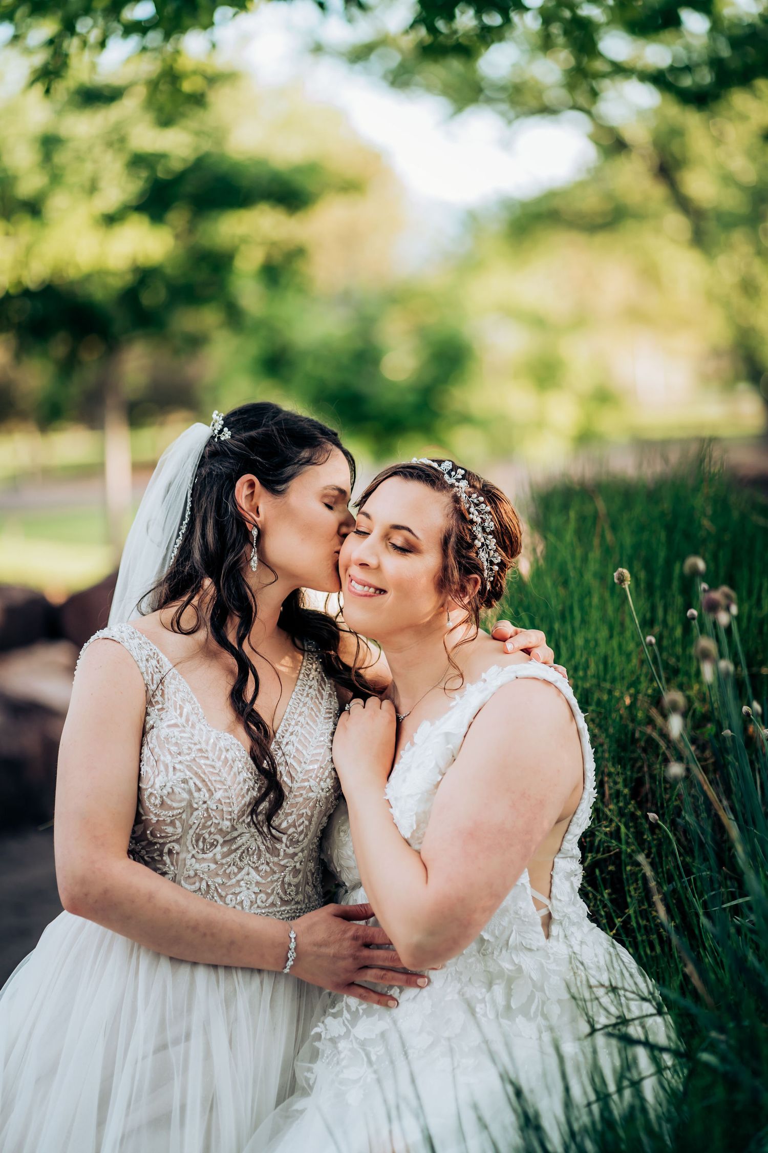 A tender moment shared between two people in white wedding dresses among spring flowers.