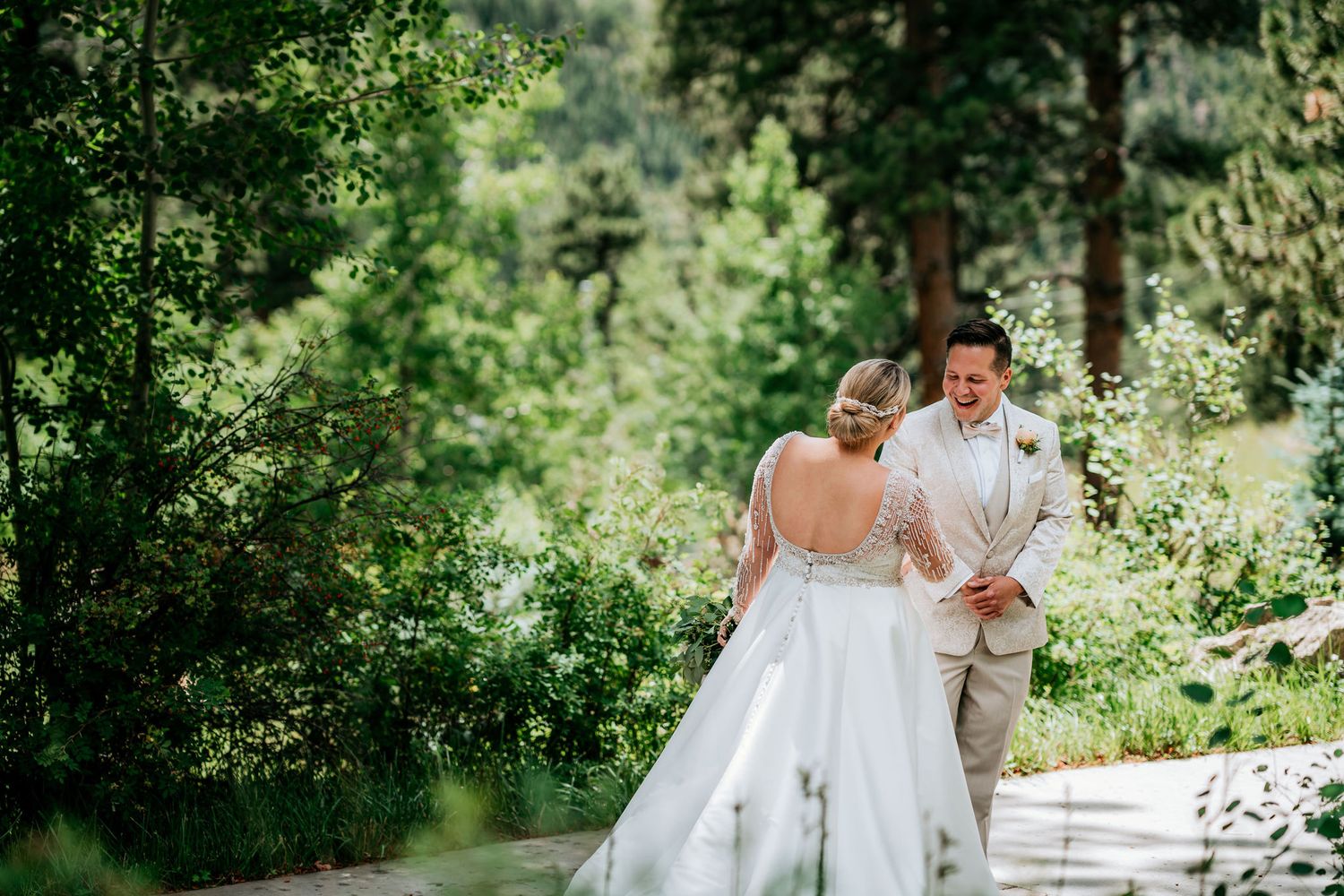 Wedding couple shares intimate moment on outdoor path surrounded by evergreens.