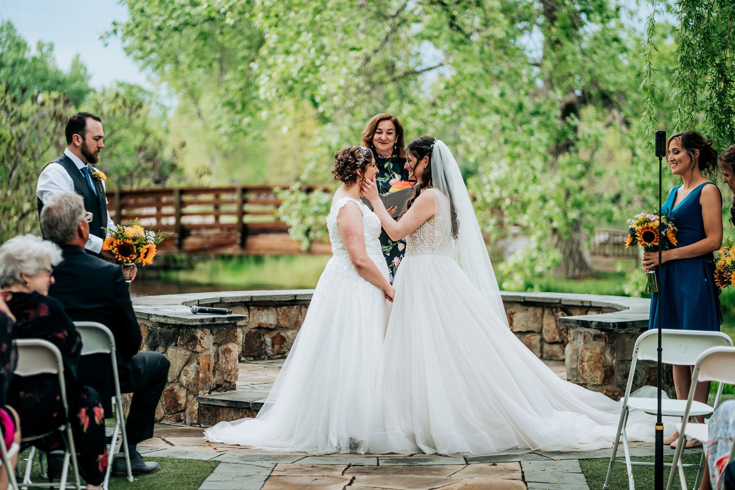Outdoor wedding ceremony in a garden setting with guests seated on chairs and stone pathway.