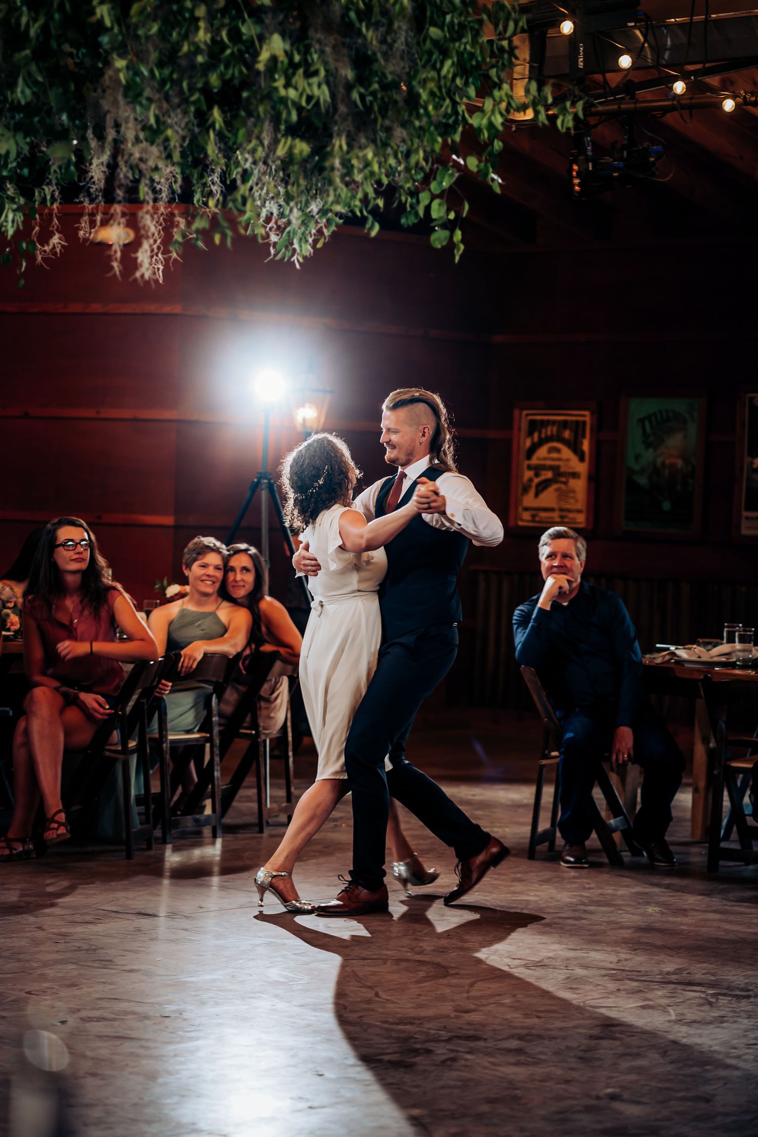 Elegant dance performance in a dimly lit venue with spectators watching from the sidelines.