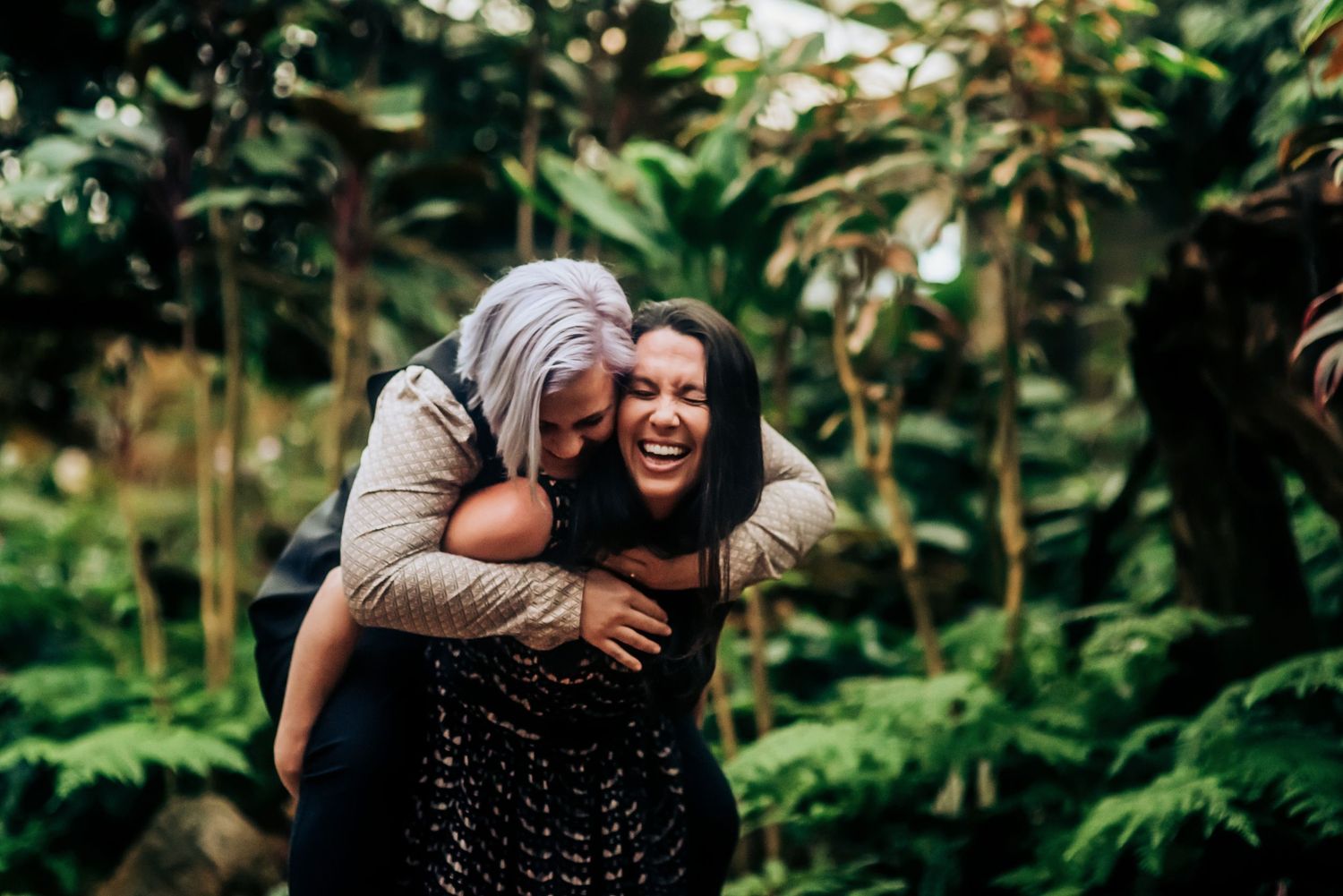 Joyful wedding party celebrating outdoors surrounded by lush tropical greenery.