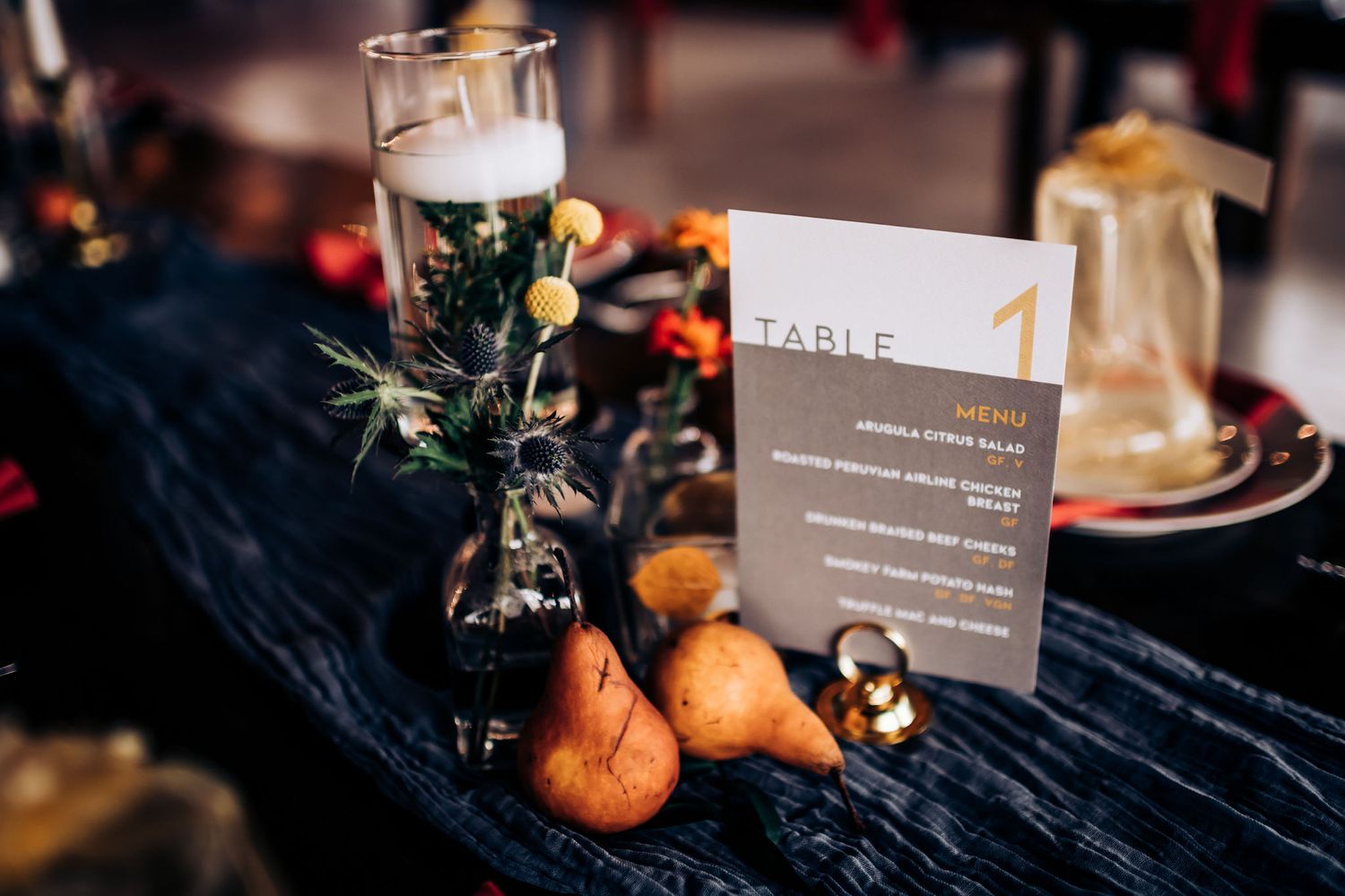 Table number one card with tangerines and wine glass on dark tablecloth.