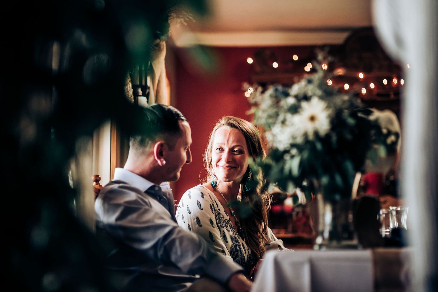 Romantic reception setting with twinkling lights and white floral arrangements creating an intimate atmosphere.