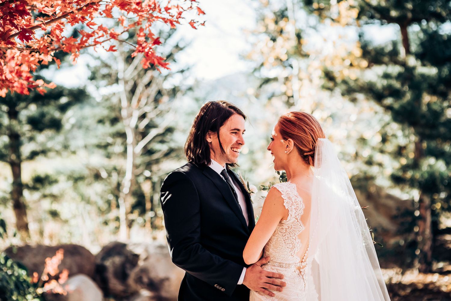 Romantic autumn wedding portrait under vibrant red maple trees.