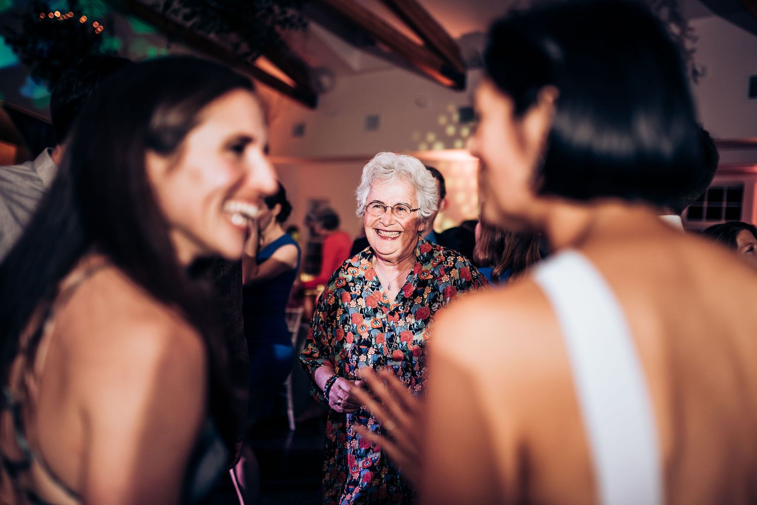 Wedding guests enjoying conversation and laughter during evening reception.