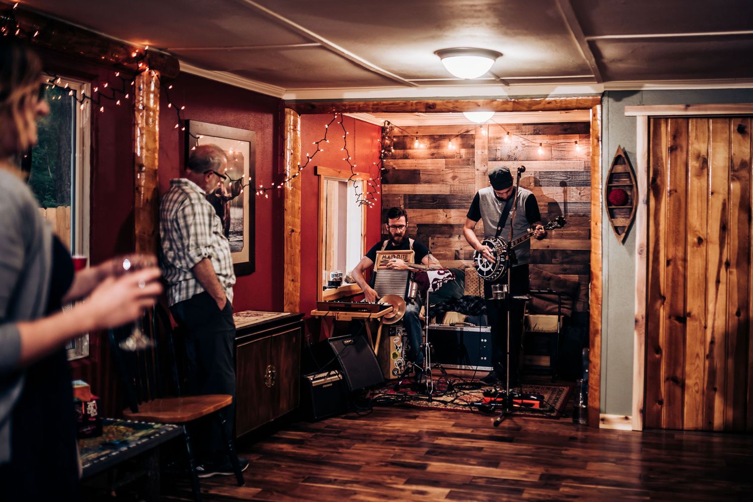 Live band performs in a cozy wood-paneled basement venue with string lights.