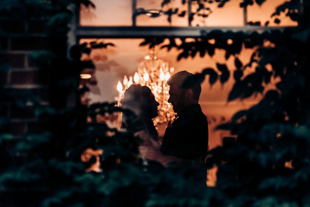 A silhouetted couple sharing an intimate moment against a sunset with glowing lights.