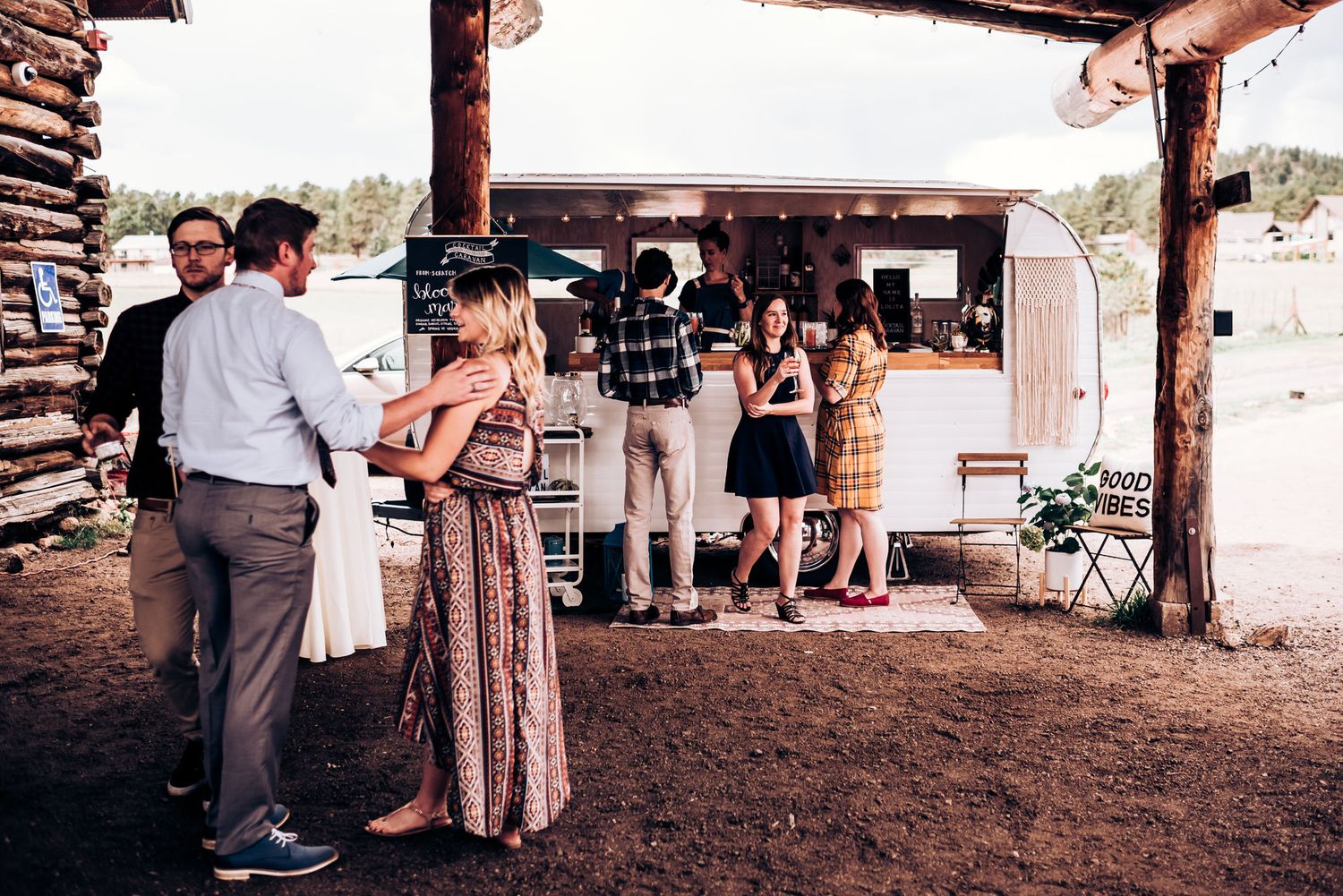 Wedding guests gathering at an outdoor rustic venue with food truck service.