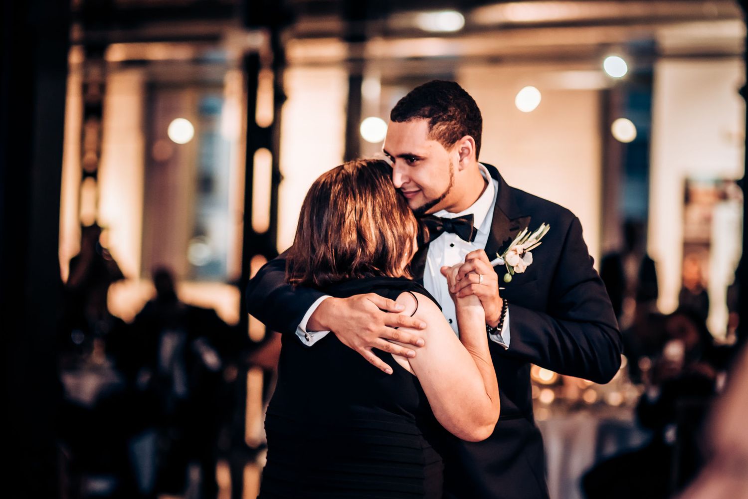 Intimate dance moment during wedding reception in dimly lit venue.