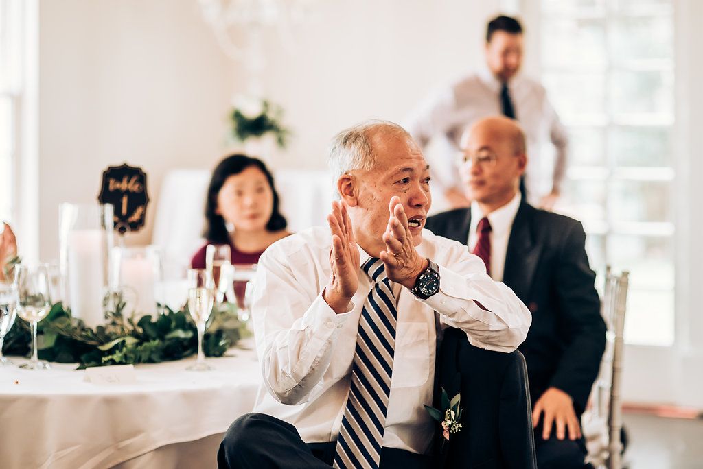 A guest shares a joyful moment while speaking during a wedding reception.