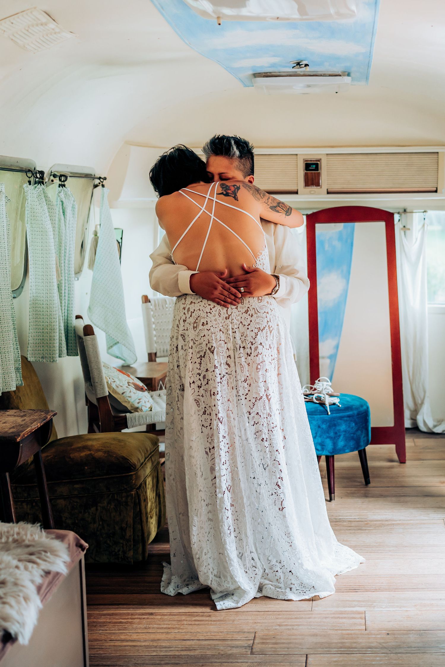 Couple embracing in a white lace dress and formal attire inside a rustic room.