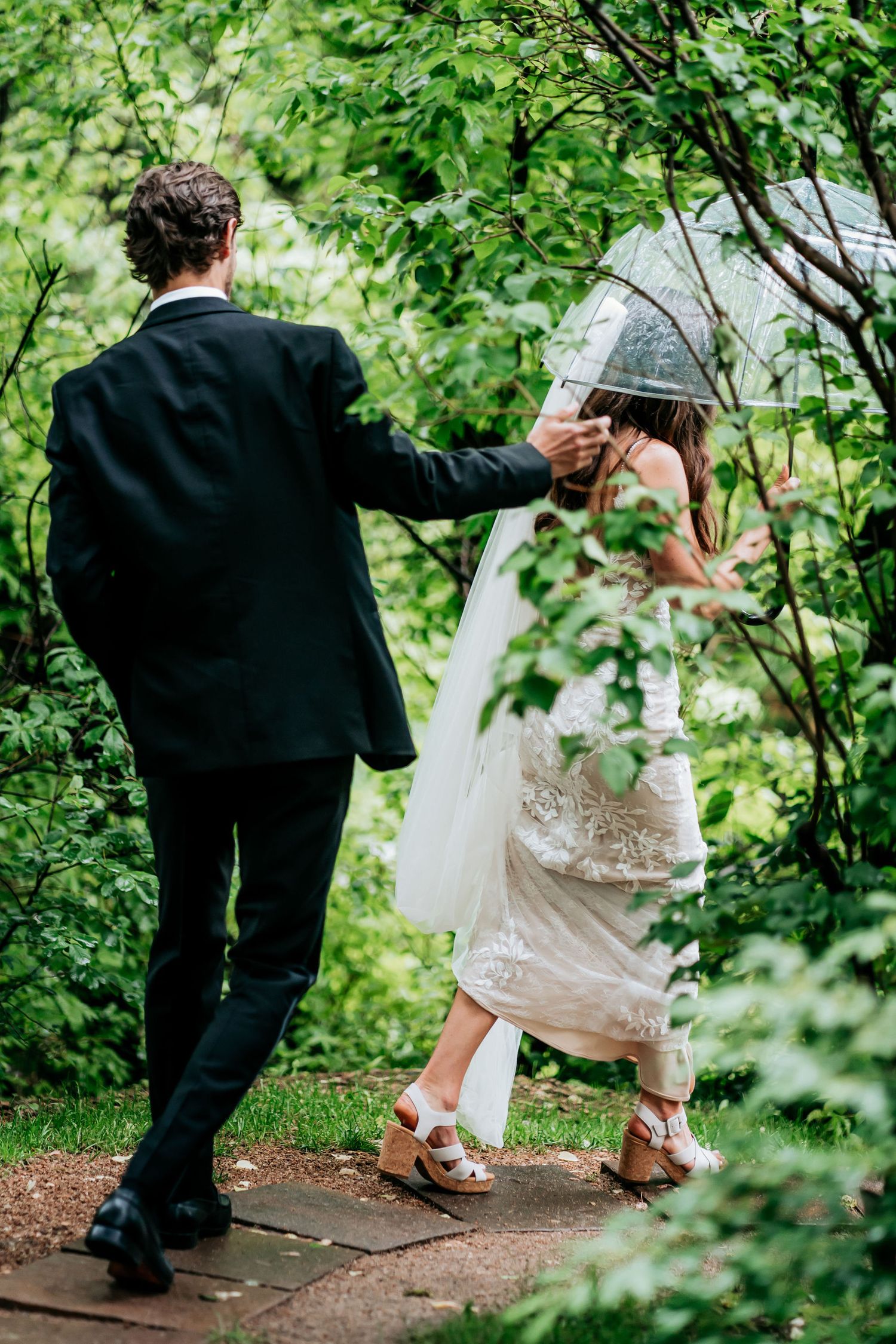 Couple walking along a garden path during their wedding photoshoot.