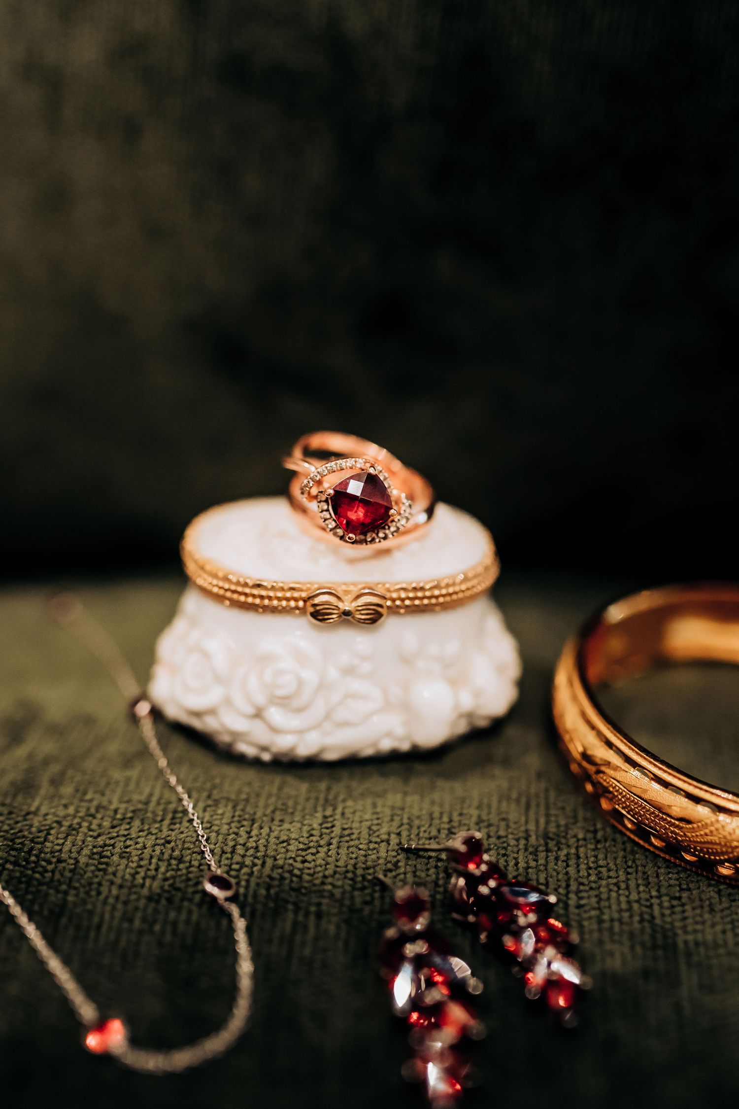 Vintage-style ring with red gemstone displayed on decorative white trinket box.