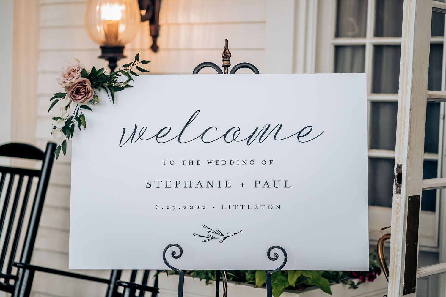 Wedding guest in navy suit holding champagne glass at venue entrance.