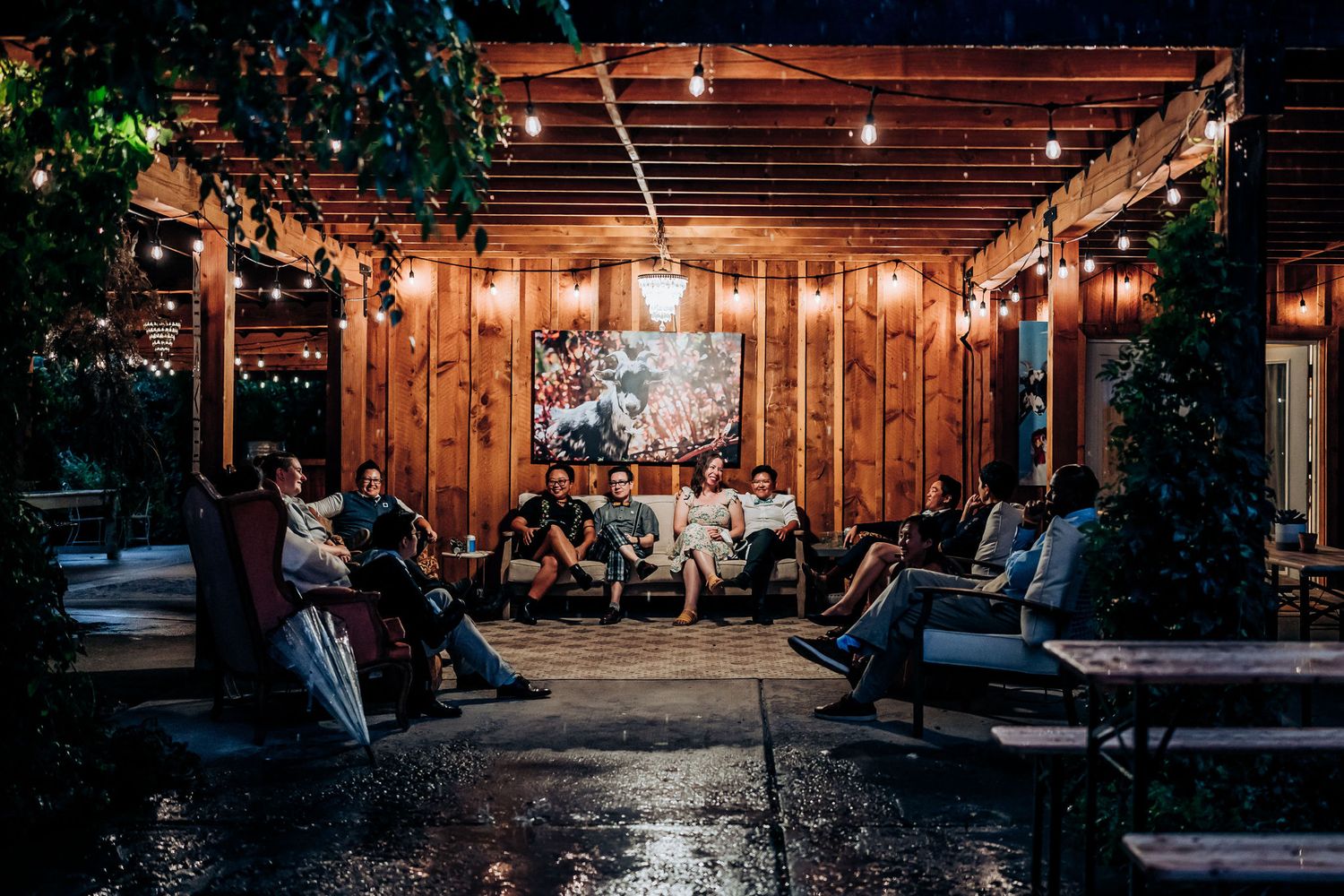 Rustic outdoor wedding reception venue with string lights and wooden walls at dusk.