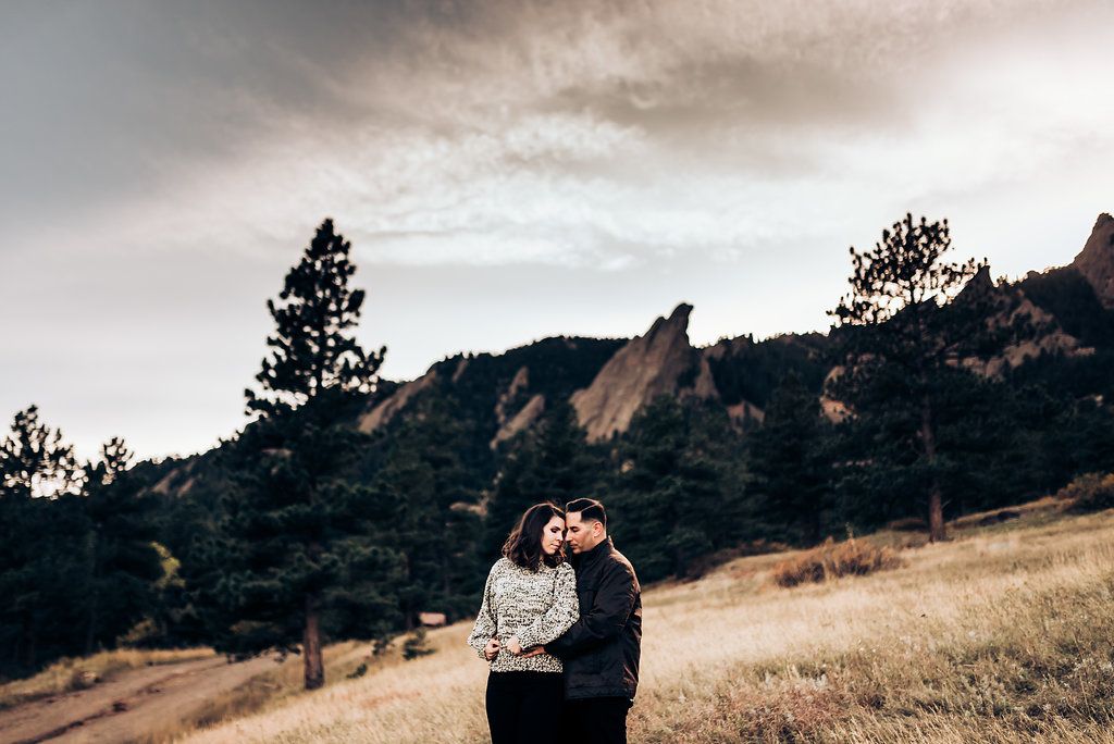 Intimate couple portrait with dramatic mountain landscape and moody sky in the background.