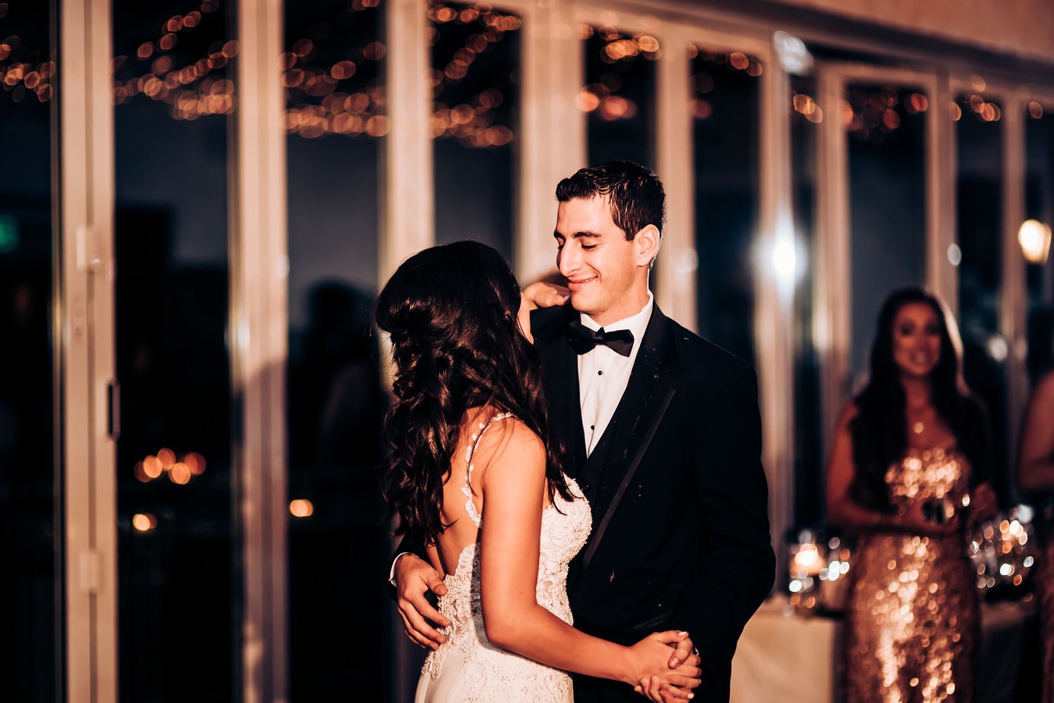 Romantic first dance moment at wedding with couple swaying beneath twinkling lights.