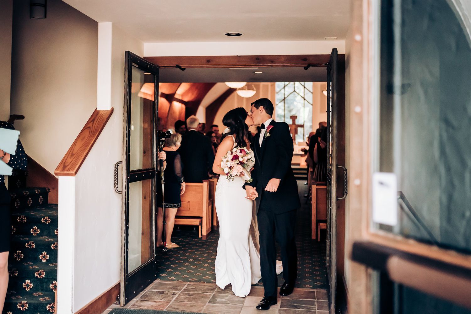 Couple enters doorway during wedding ceremony while guests look on.