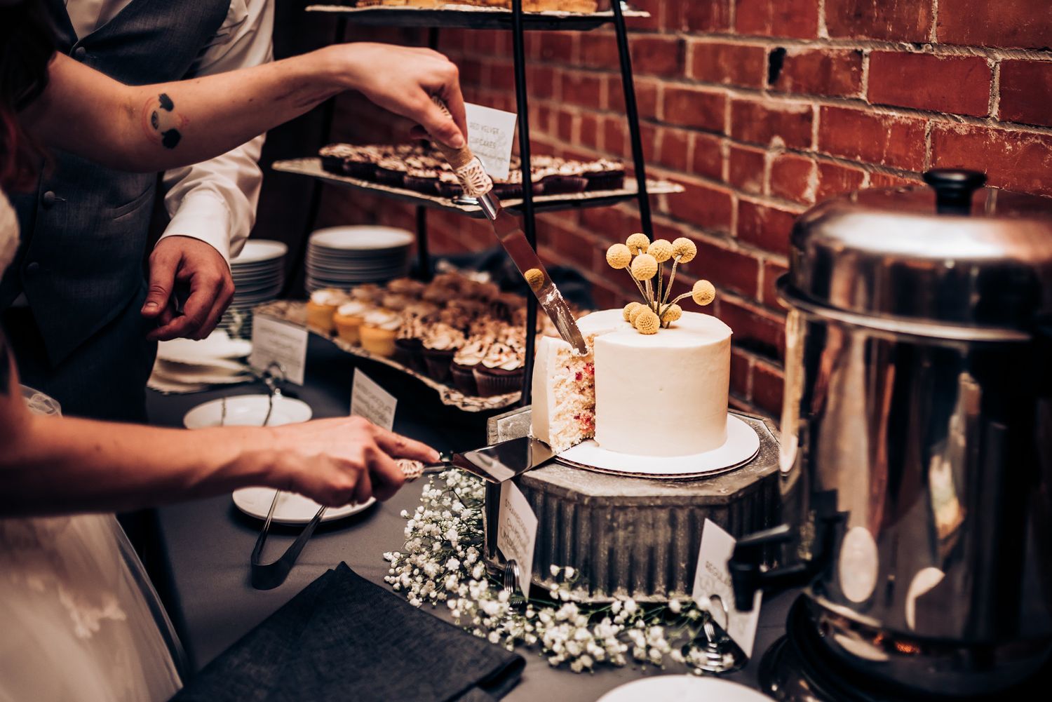 Dessert station with wedding cake and other treats being served at reception.