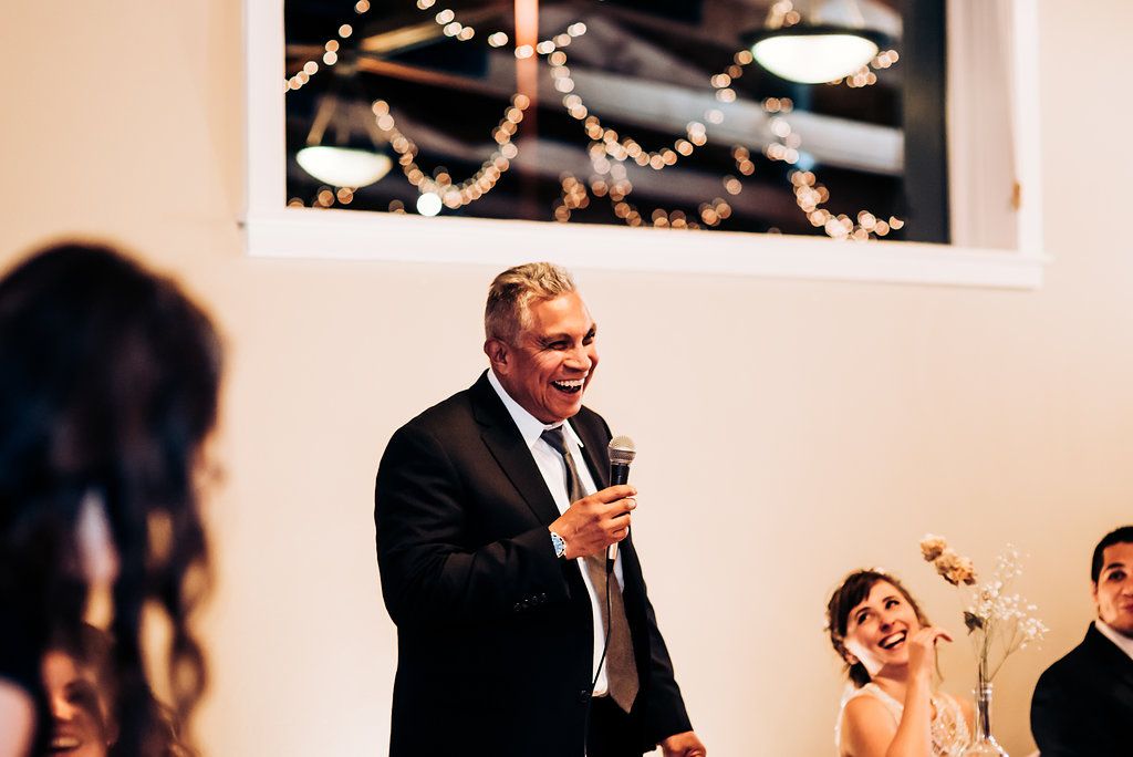 Wedding reception speech moment with string lights decorating the ceiling.