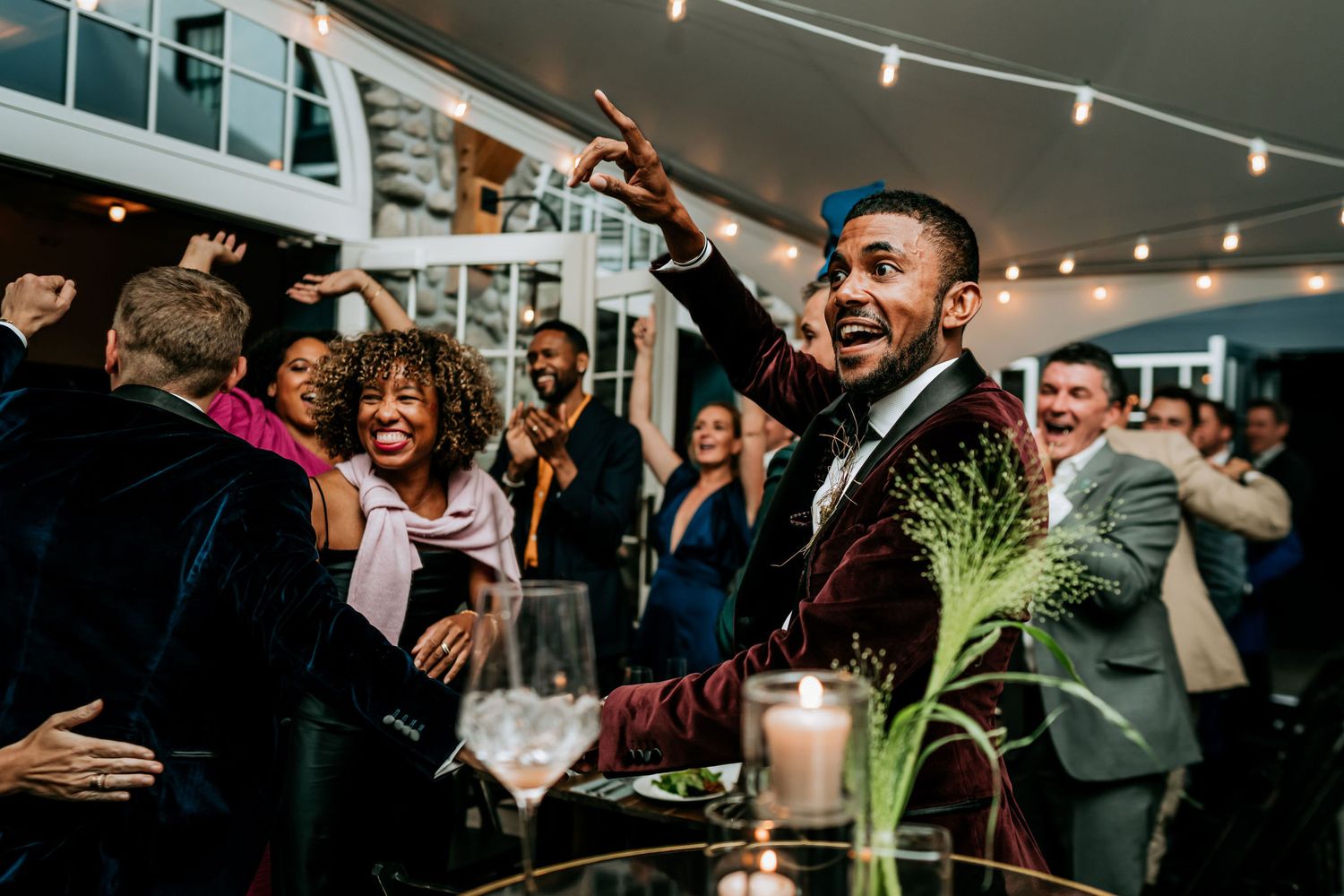 Celebratory moment with party guests dancing and cheering in a festively lit indoor venue.