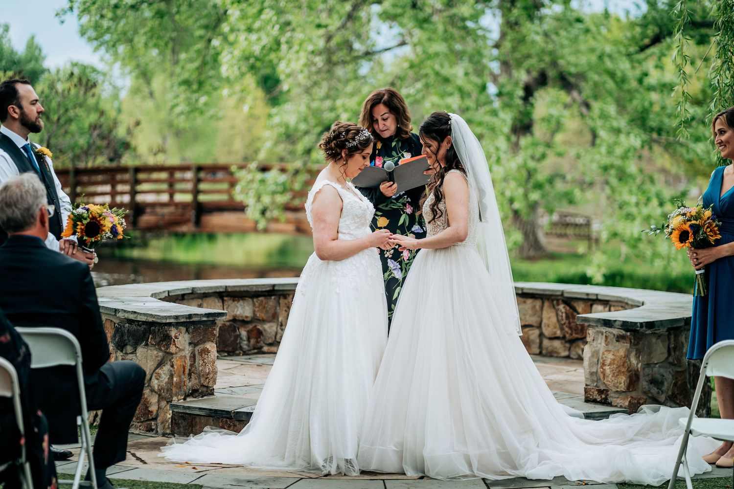 Wedding ceremony outdoors with natural greenery and stone pathway backdrop.