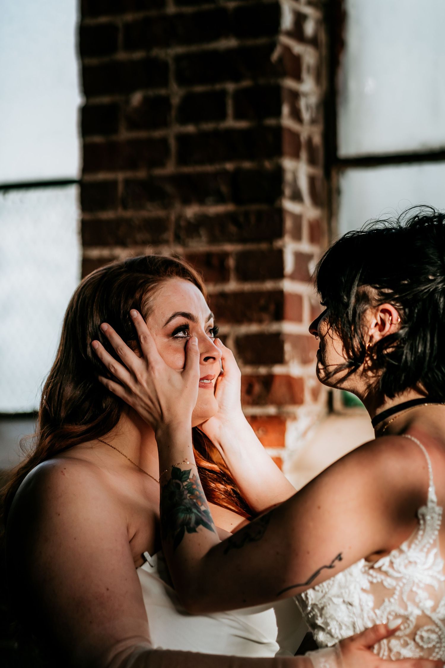 Emotional wedding scene with intimate embrace against brick wall background.