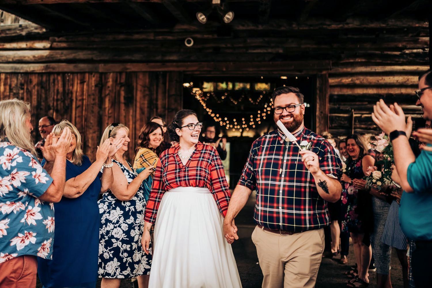 Wedding reception celebration with guests dancing in rustic barn venue.
