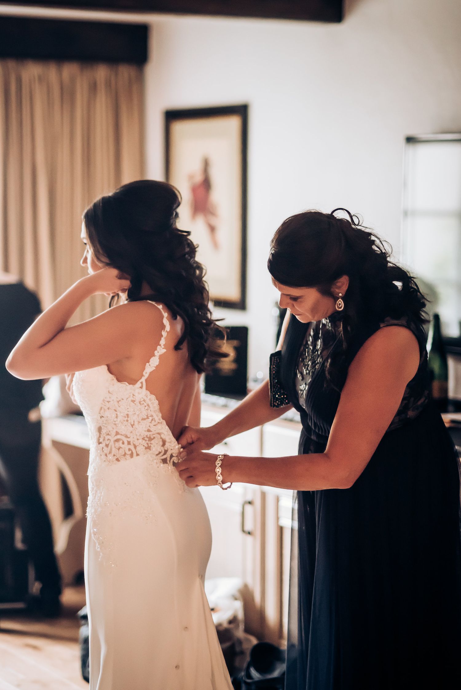 Wedding dress final adjustments being made in a sunlit room.