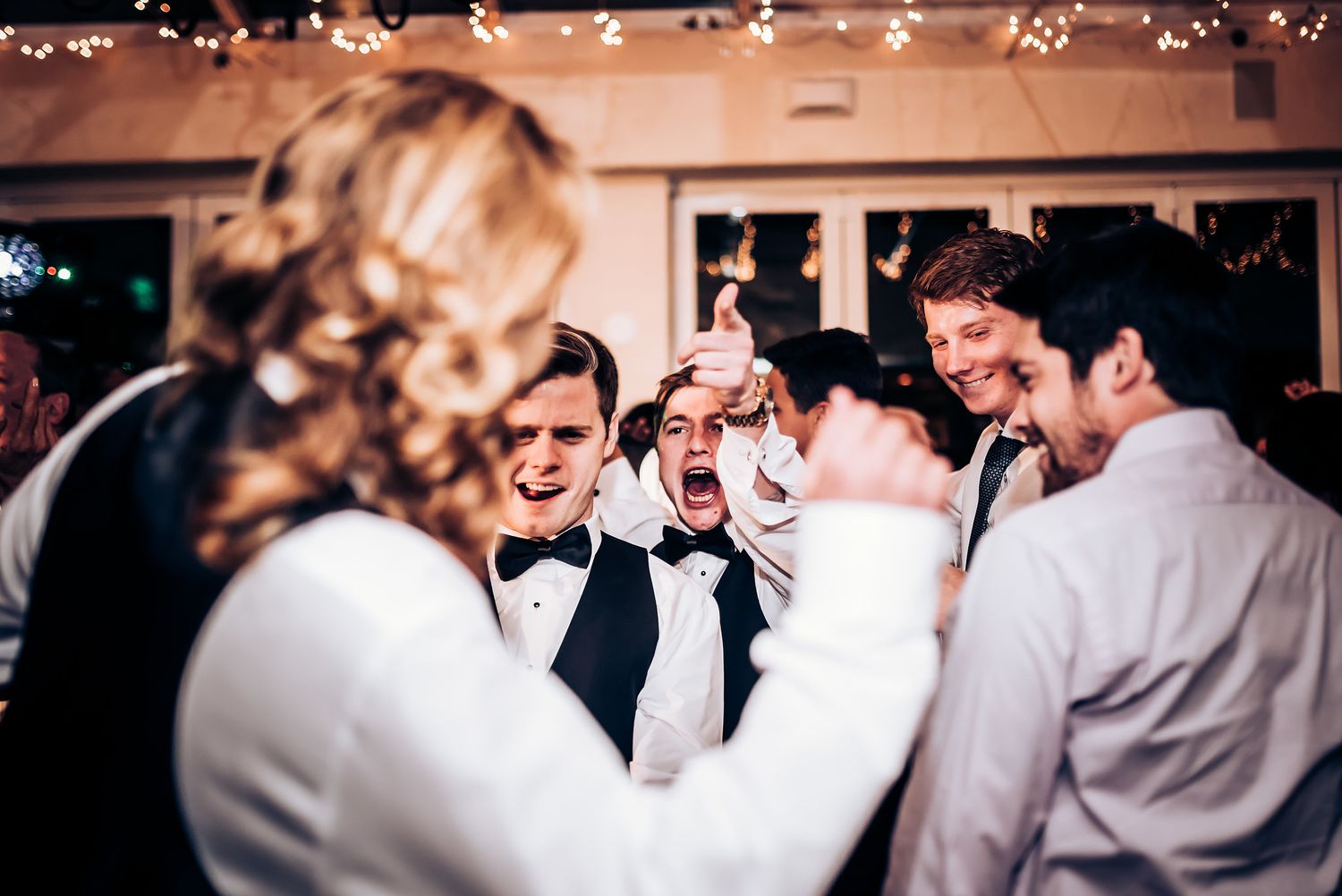 Wedding guests in formal attire celebrate during lively reception moment.