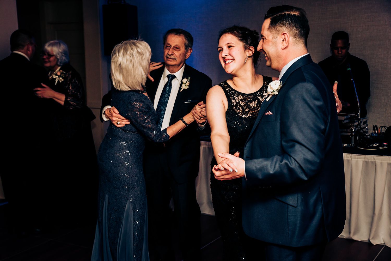 Guests dancing and laughing together at an evening wedding reception.