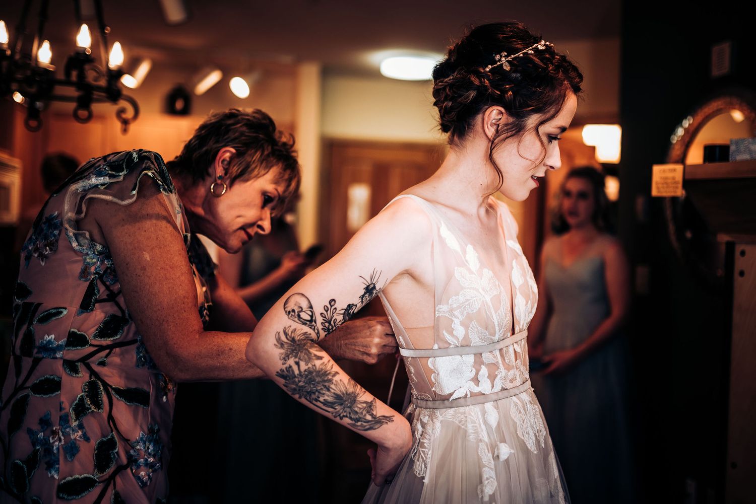 Bride in white lace dress getting final dress adjustments before the ceremony.