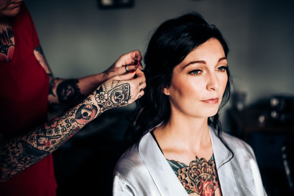 Close-up of tattooed hands styling hair with elegant lace details in frame.