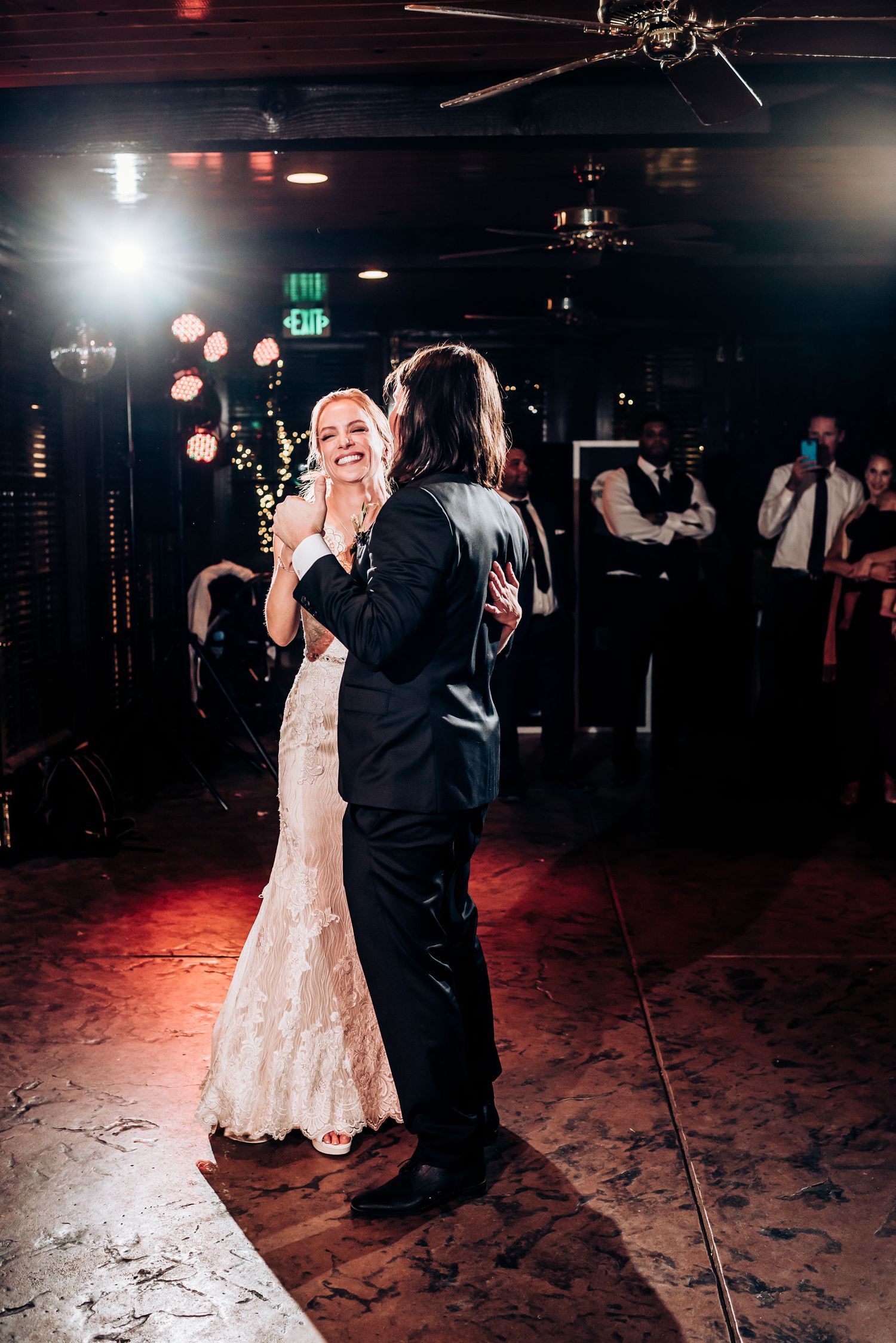 A couple dancing at their wedding reception with soft lighting and bokeh effects in the background.