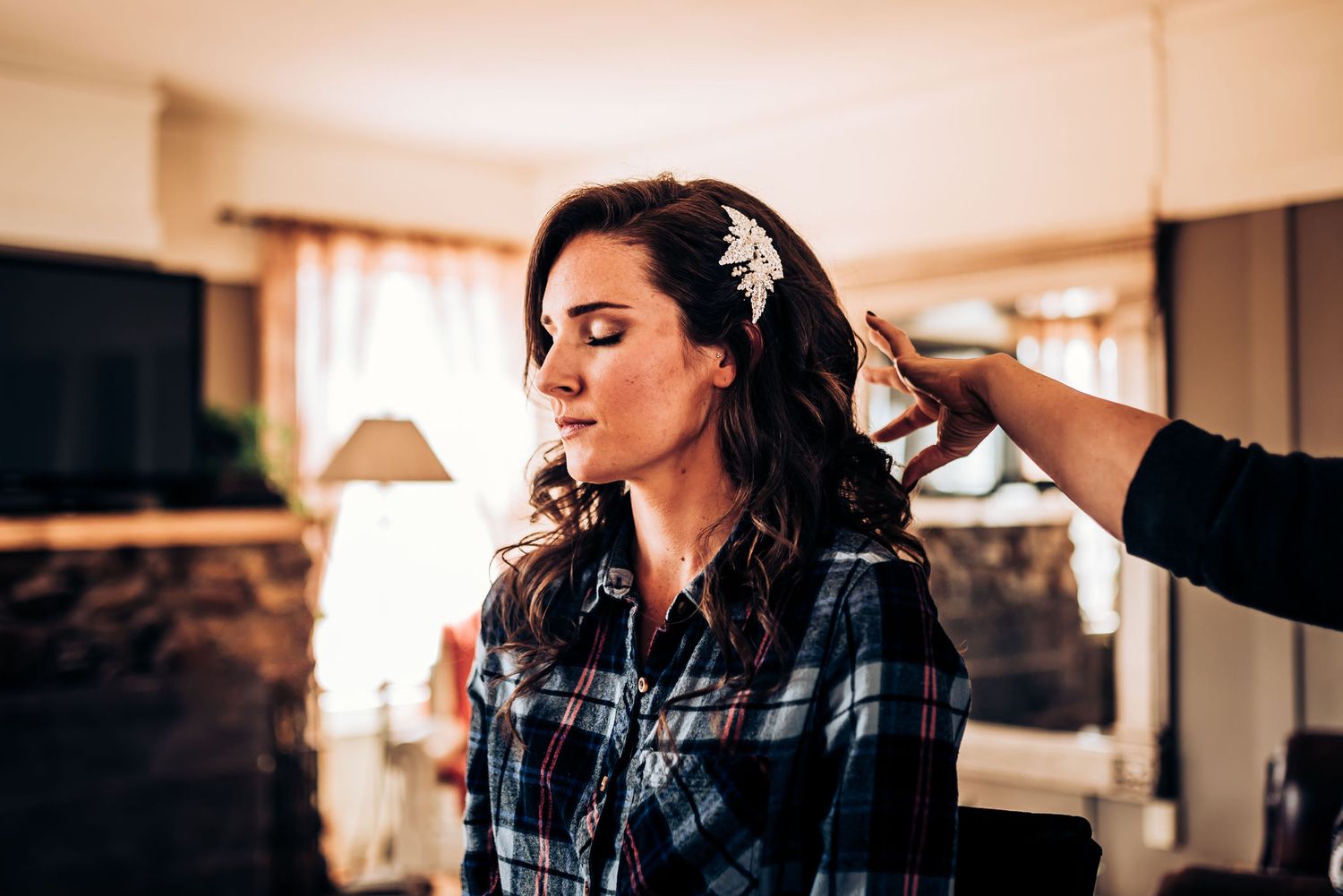 A wedding preparation scene showing hair styling in progress in a warmly lit room.
