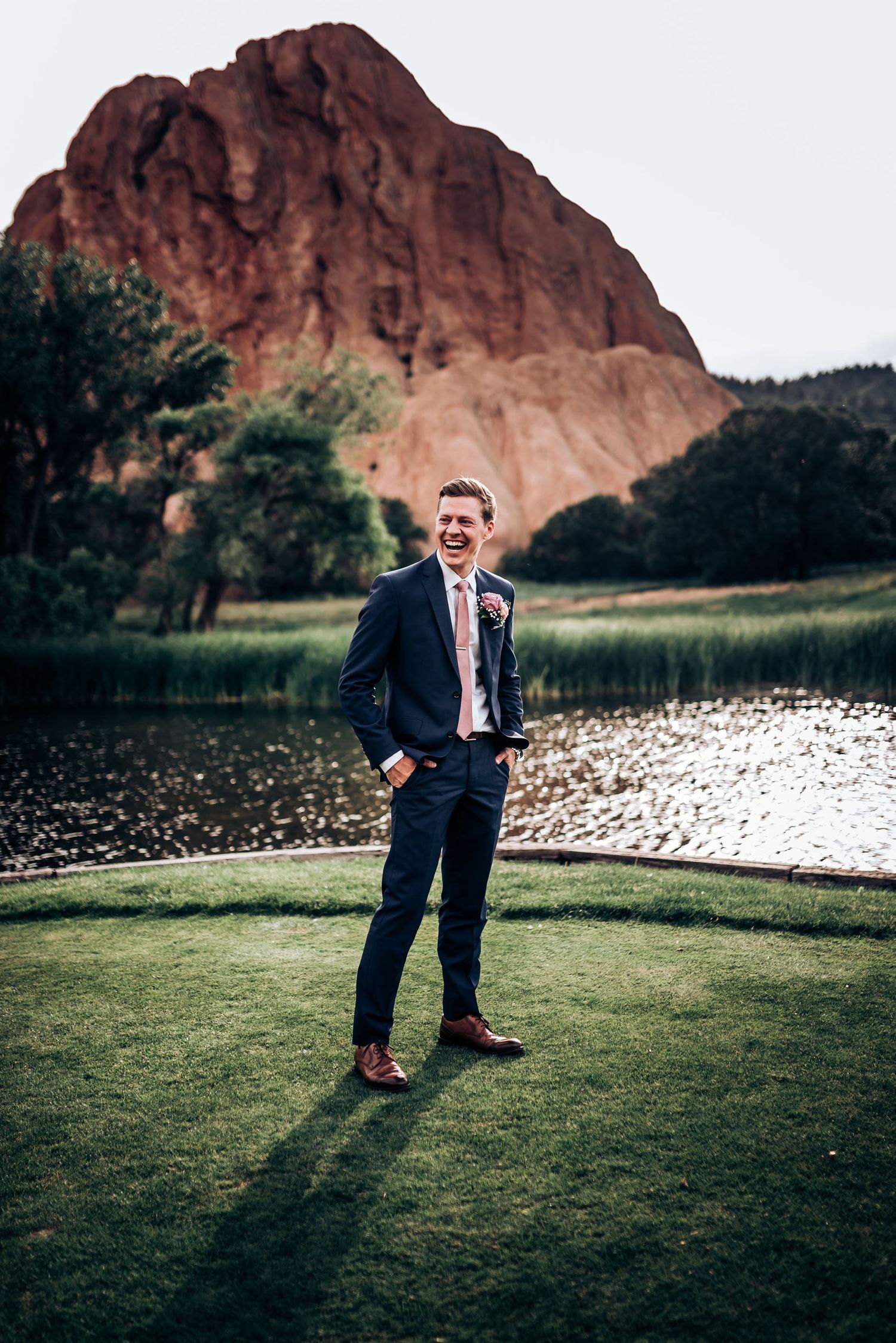 Formal portrait in navy suit against stunning red rock formation and lake landscape.
