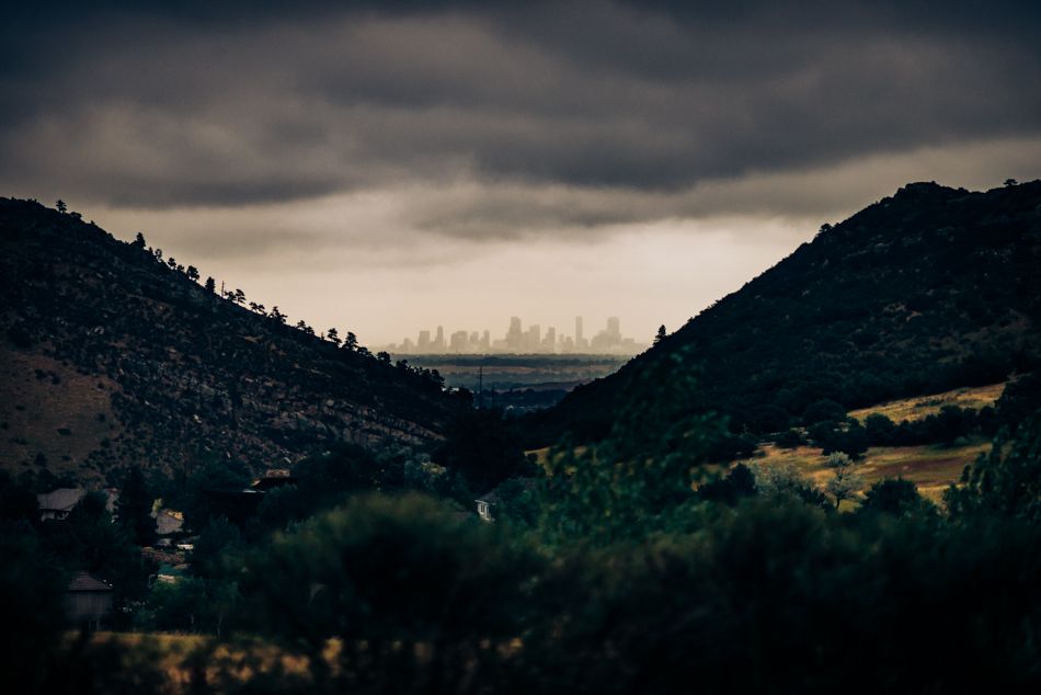 Dramatic cityscape view between mountain peaks under stormy skies.