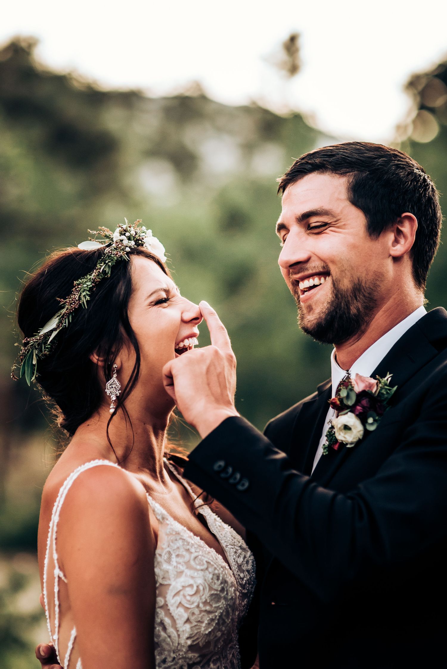 Joyful candid moment between newlyweds sharing laughter during outdoor wedding photoshoot.