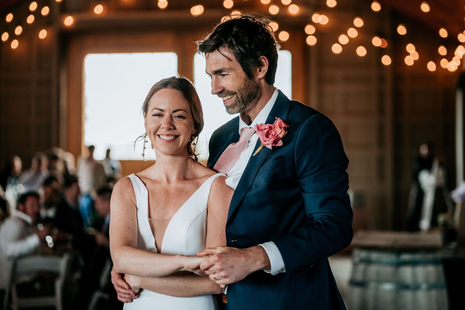 A couple shares a joyful first dance moment under twinkling lights at their wedding reception.