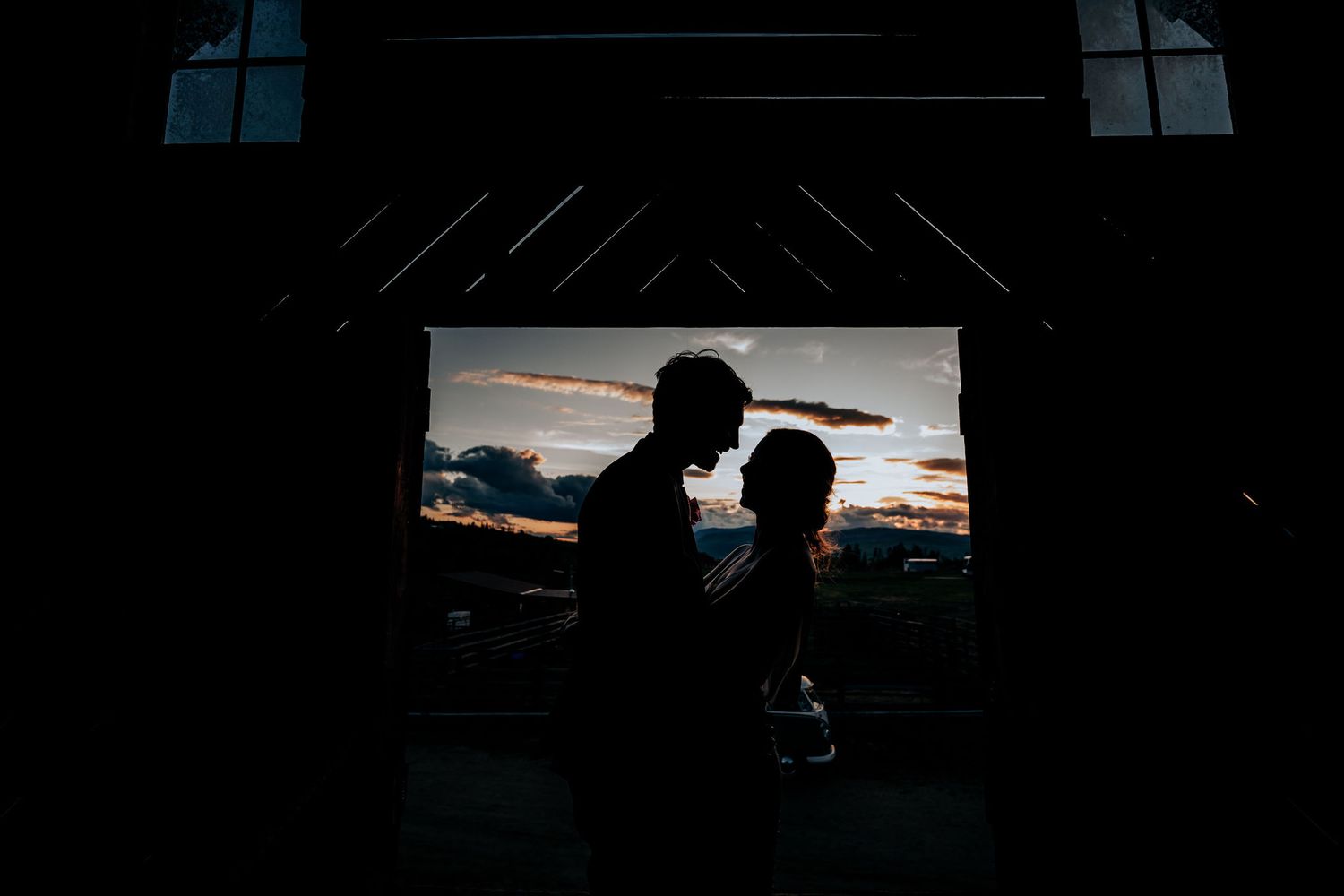 Romantic silhouettes framed by window during golden sunset hour.