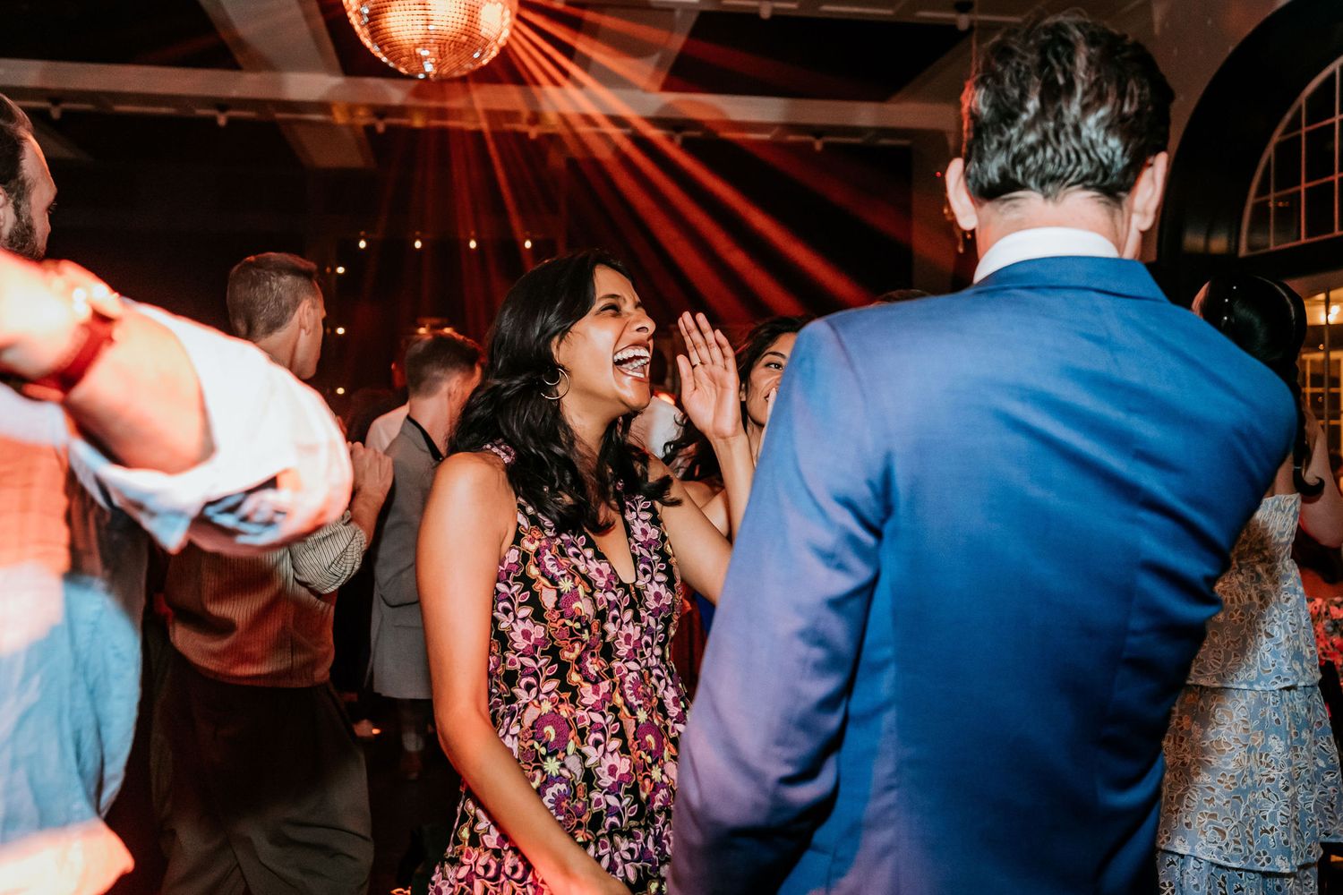 Dance party scene with red lighting and guests enjoying themselves on the dance floor.