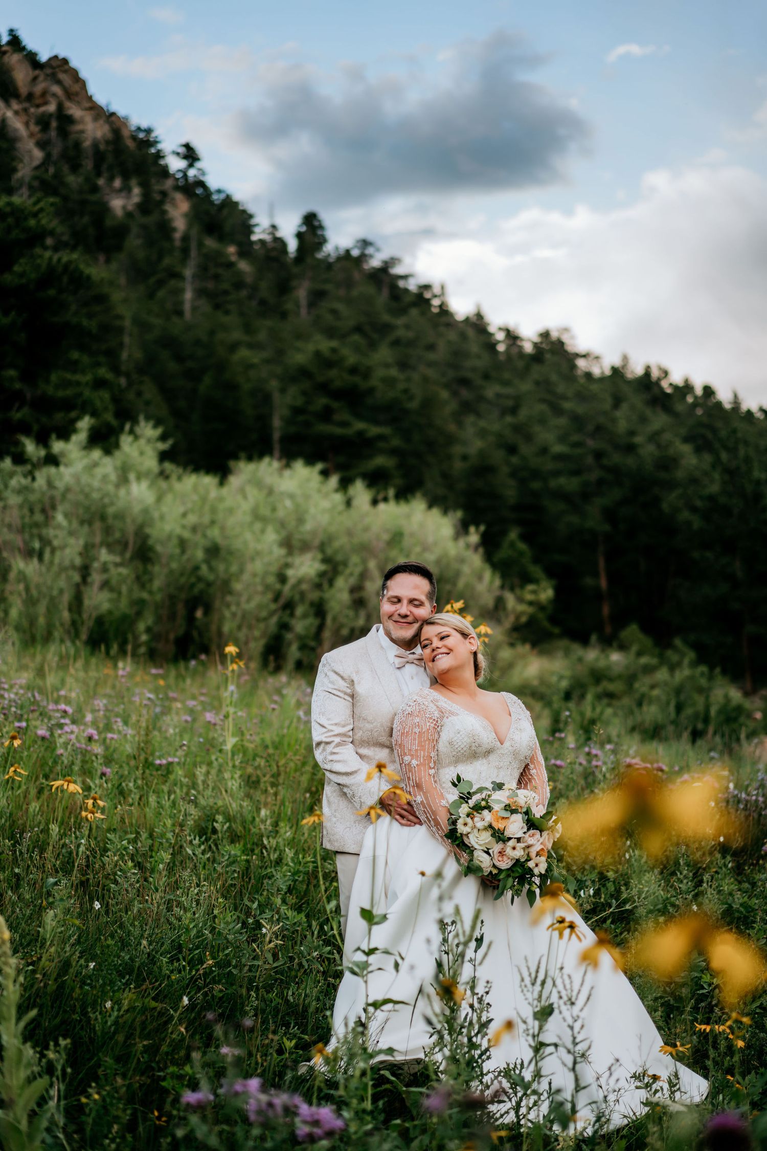 Wedding portrait in mountain meadow with wildflowers and natural scenery.