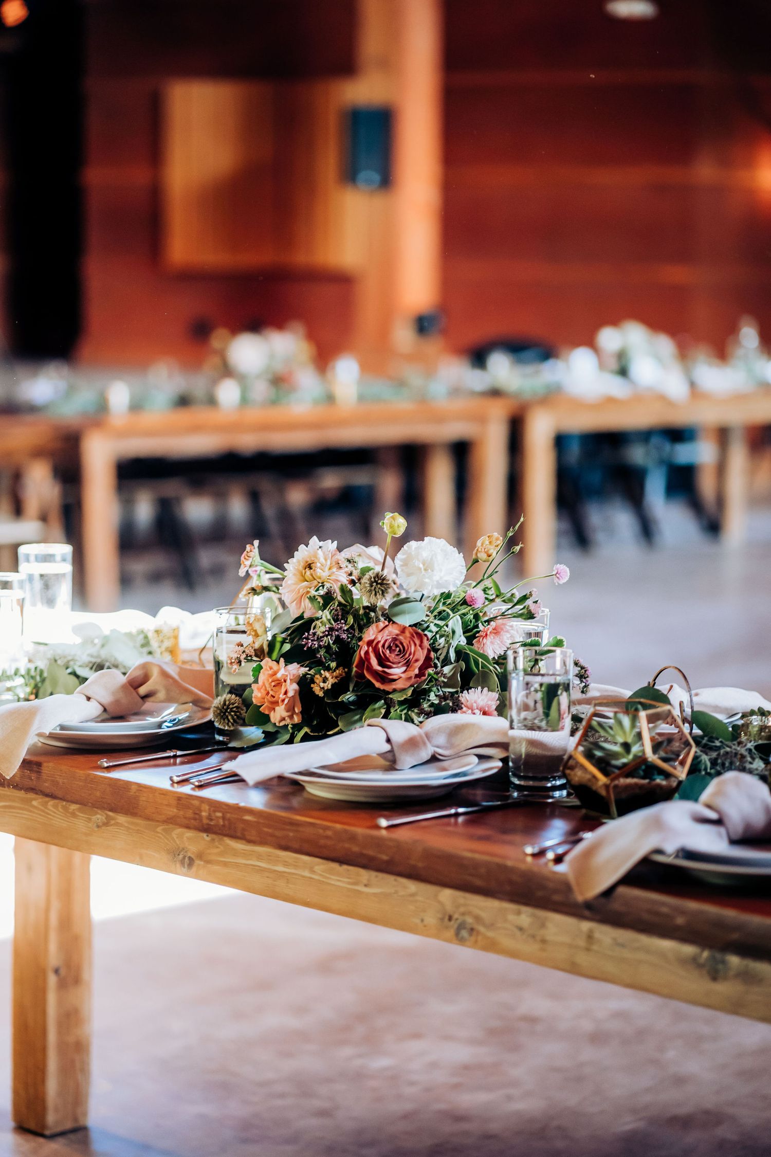 Rustic wooden farm table decorated with romantic floral centerpieces and place settings.