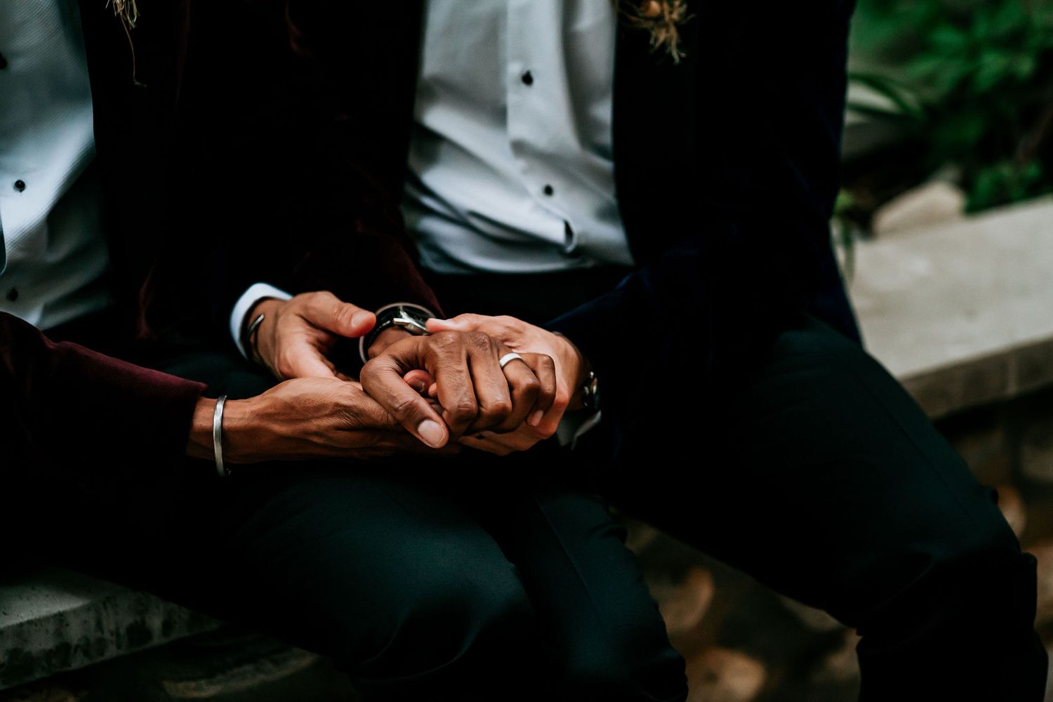 Close-up of intertwined hands with wedding rings showing tender connection.