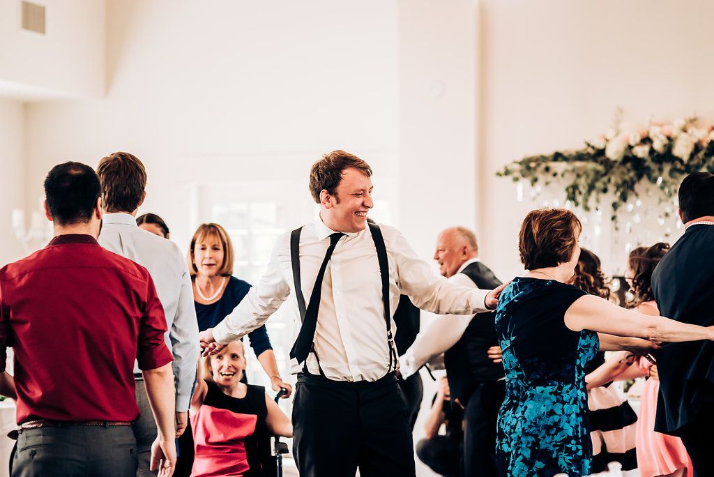 Wedding guests dancing and socializing at a lively reception with people in formal attire.