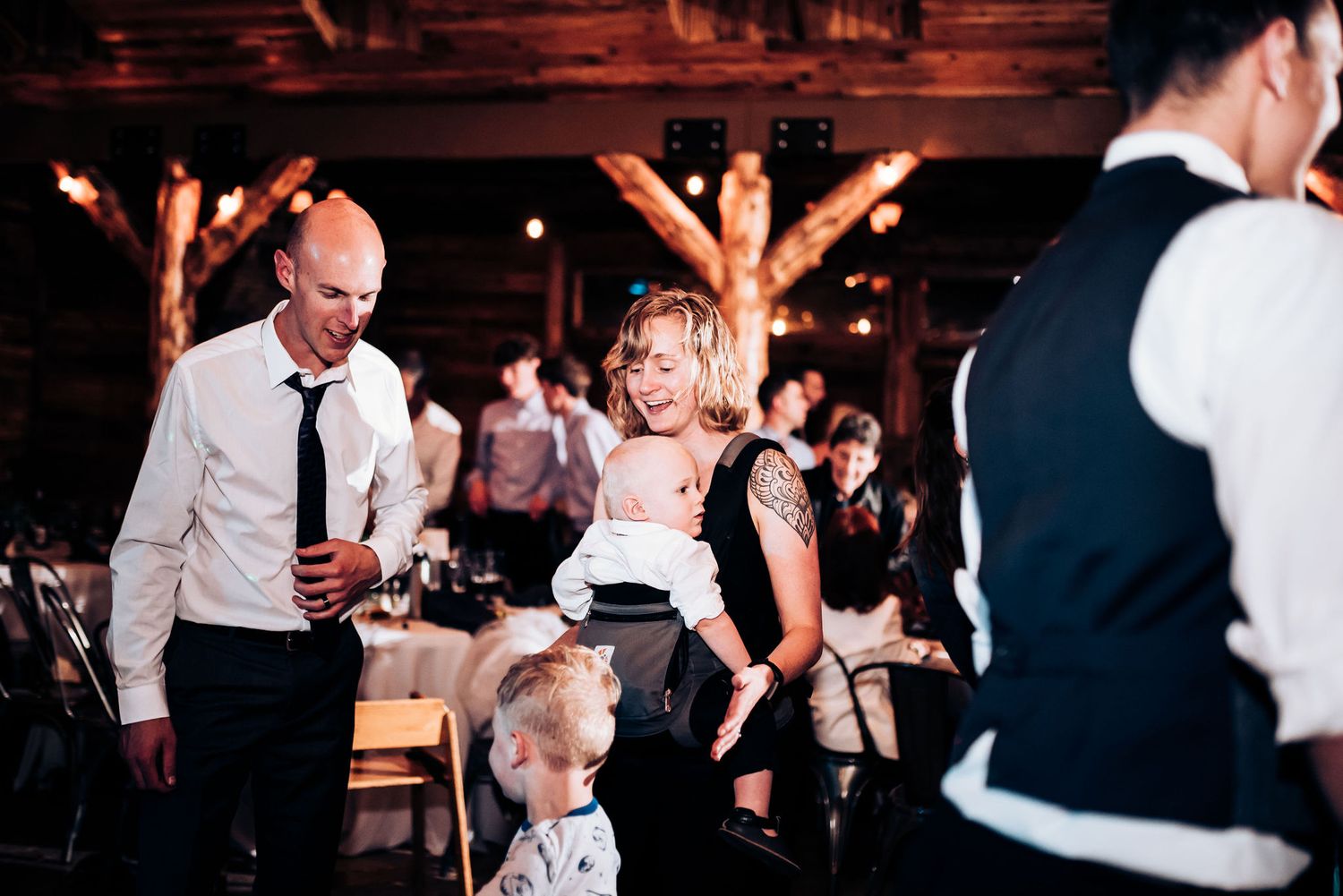 Guests enjoying an energetic dance party at a rustic wood-beamed wedding reception venue.