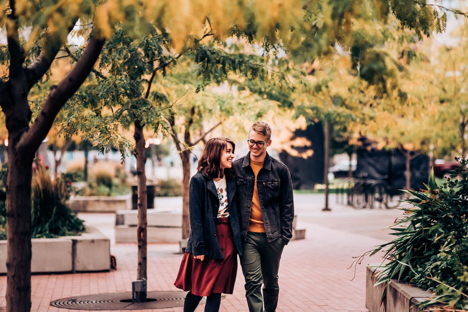 Couple walking together on urban sidewalk during autumn.