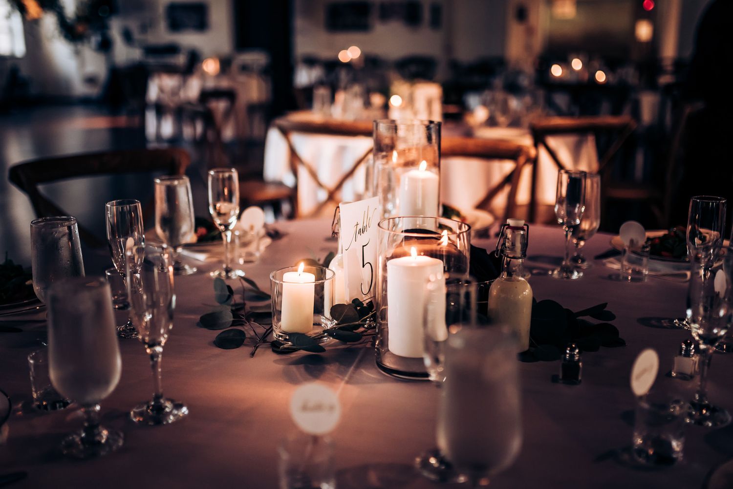 Elegant wedding reception table setting with glowing candles and wine glasses.